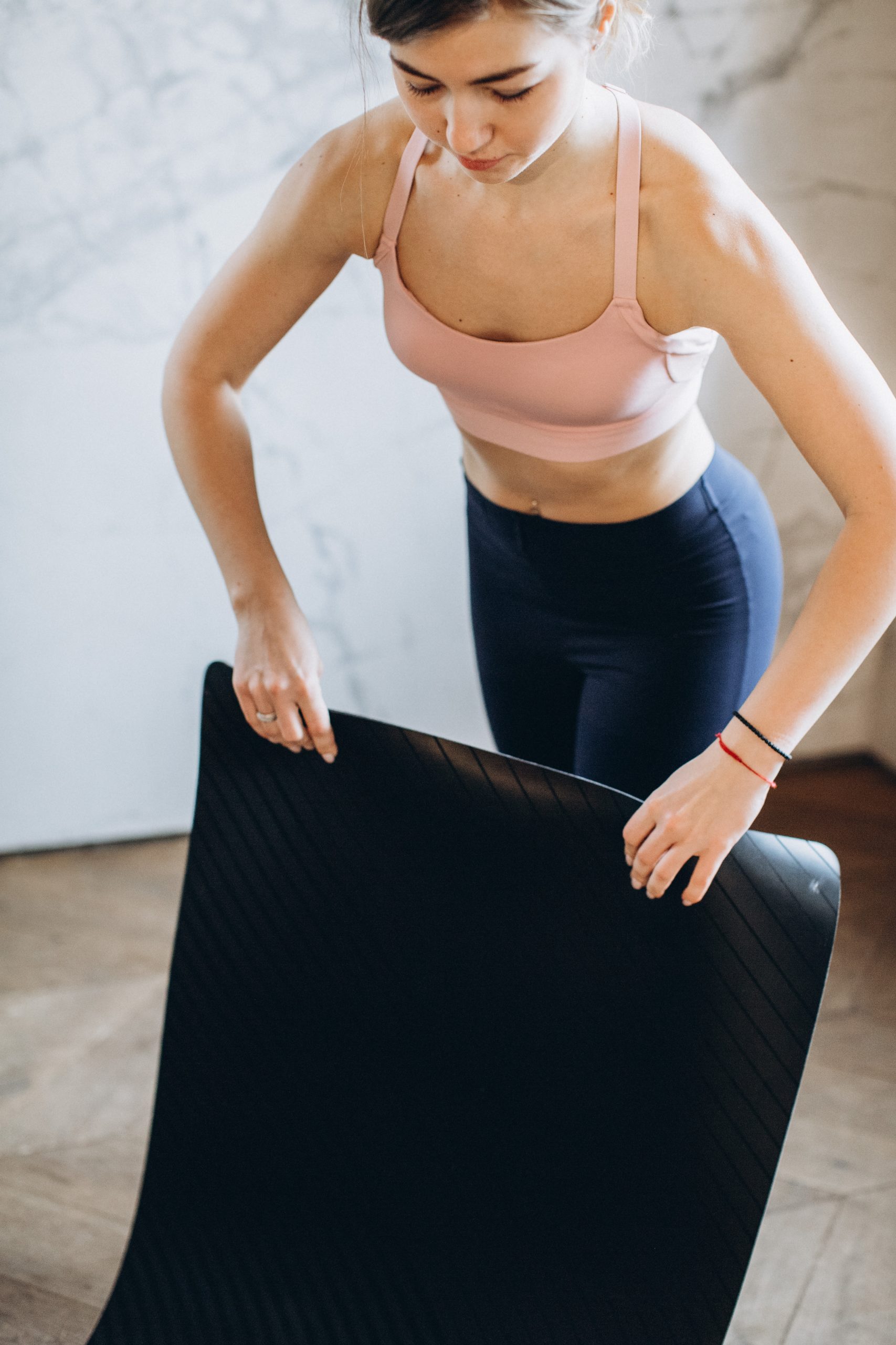 A woman rolls out a black yoga mat